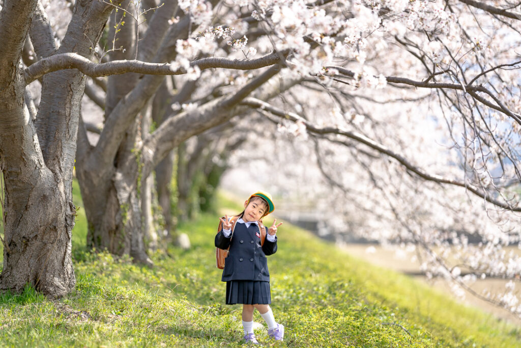 手取川の桜の樹の下で記念撮影をする新入生
