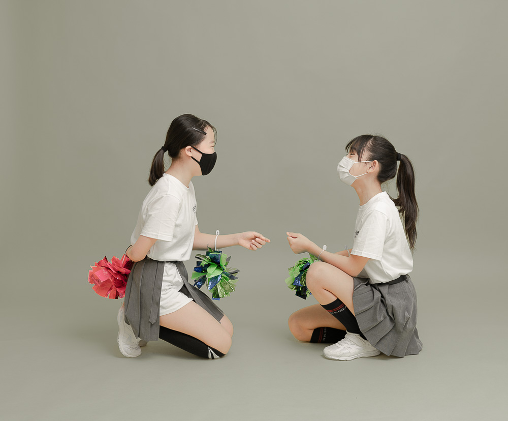 スタジオでグレー背景紙の上に座るチアリーディング