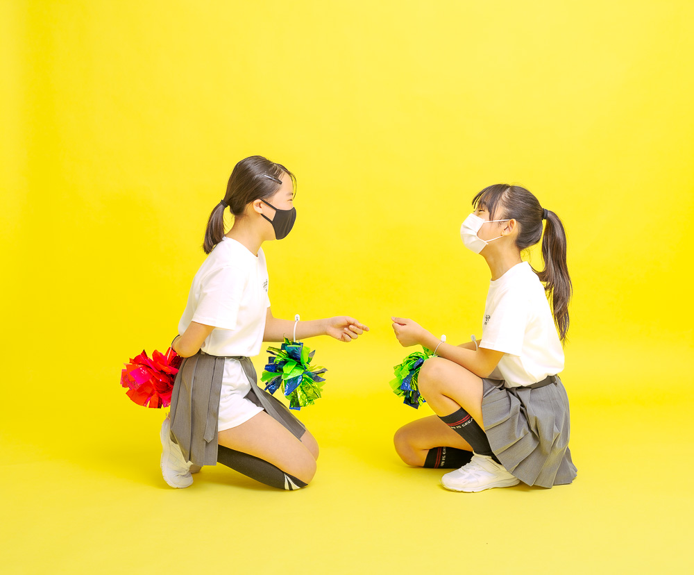 スタジオで黄色背景紙の上に座るチアリーディング