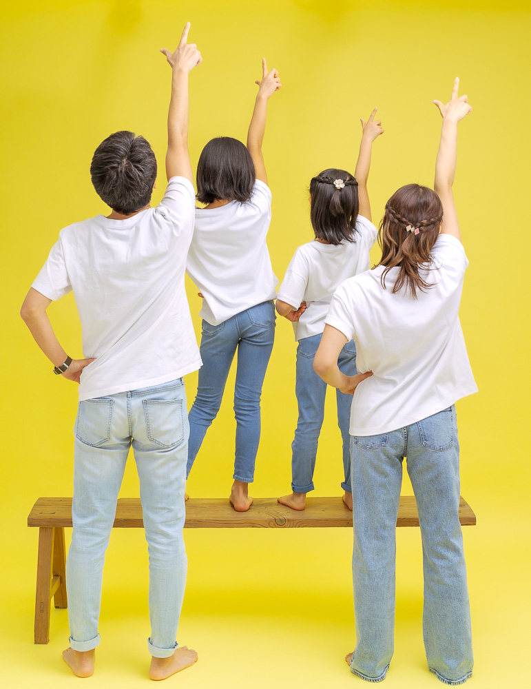 スタジオで黄色背景紙で手をあげる親子