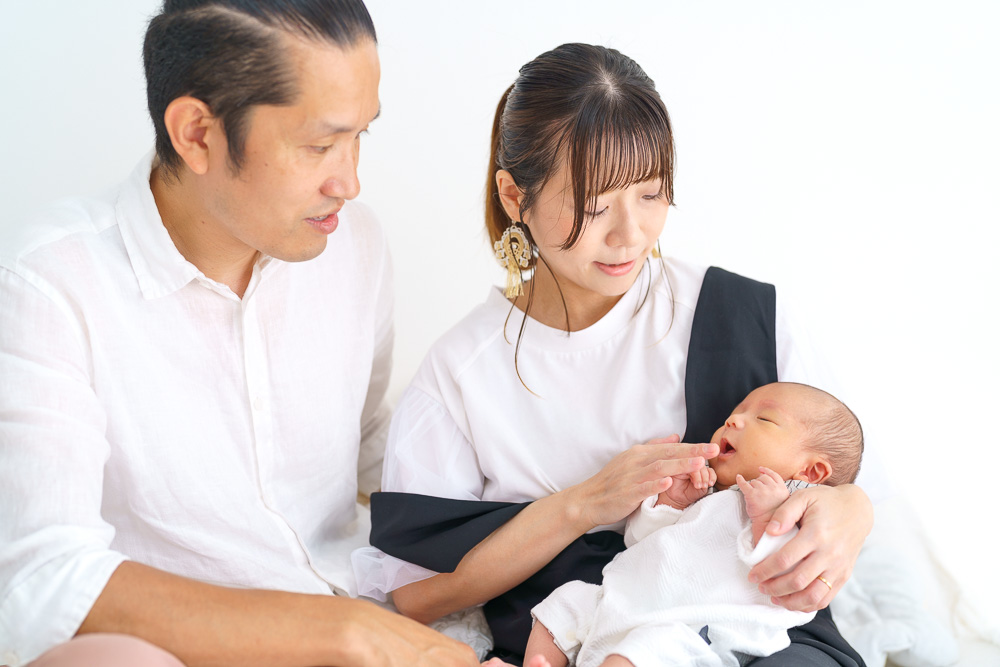 白い服で統一された夫婦と新生児