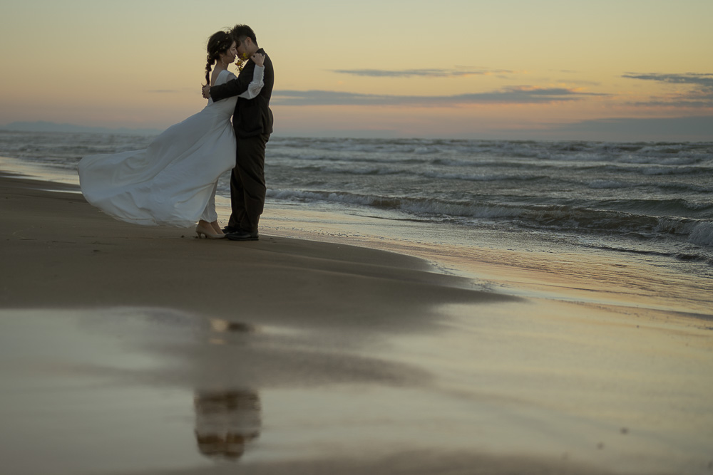 夕暮れに口づけをする新郎新婦の写真