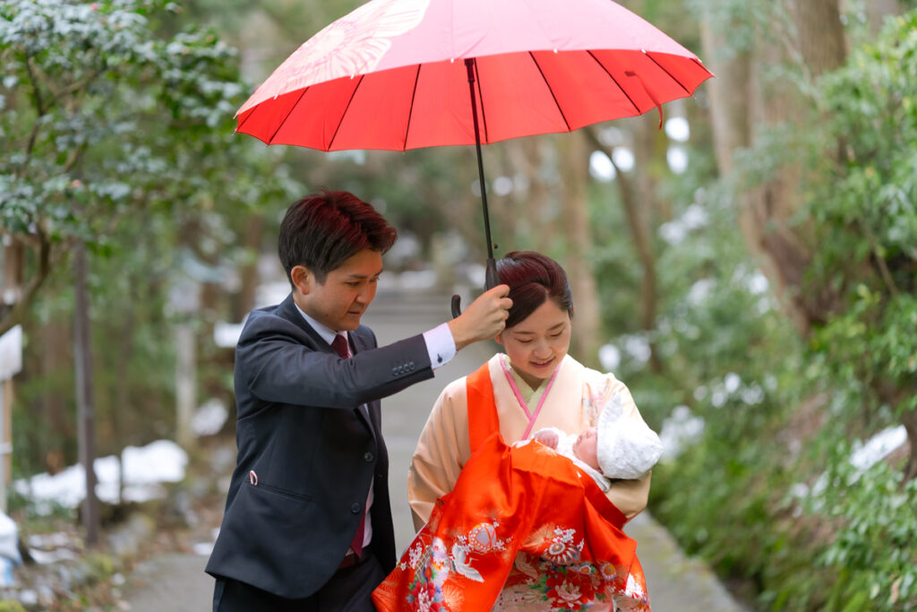 傘をさすパパと、乳児とママ