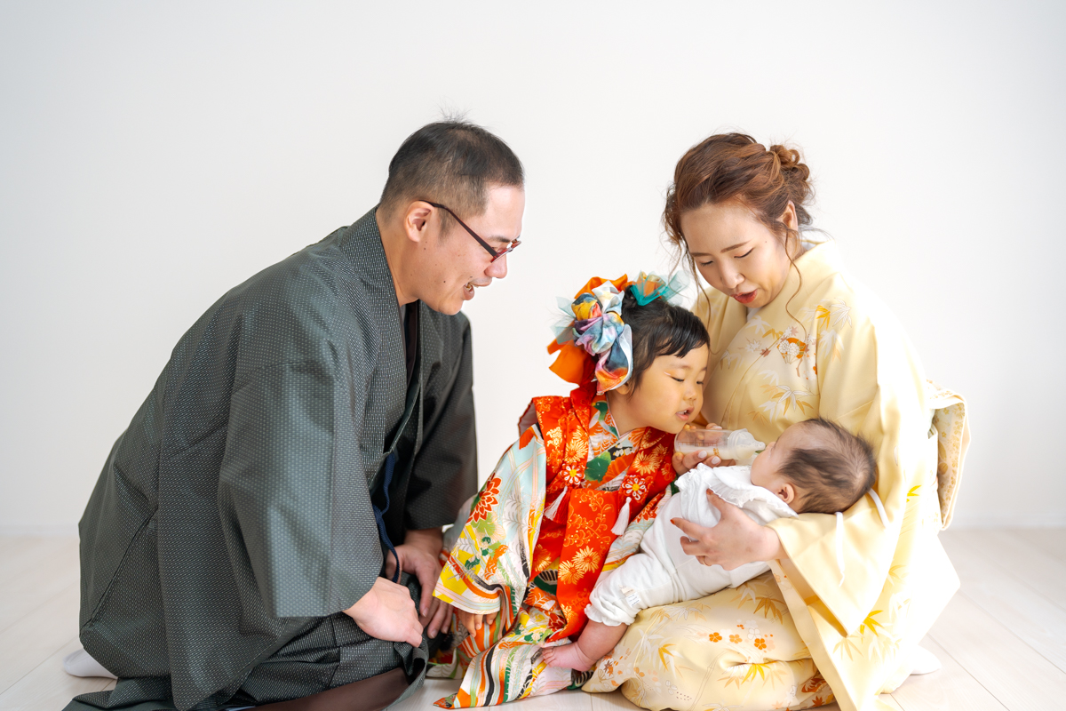 新生児を抱く着物の親と七五三の姉