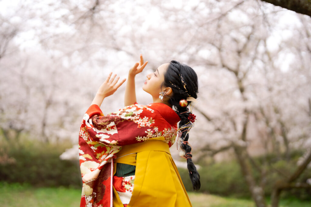 桜の下でポーズをとる卒業袴の女性