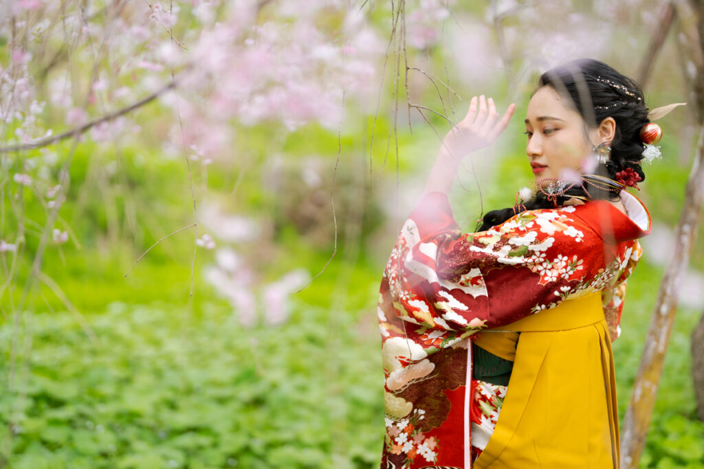 桜の下でポーズをとる卒業袴の女性