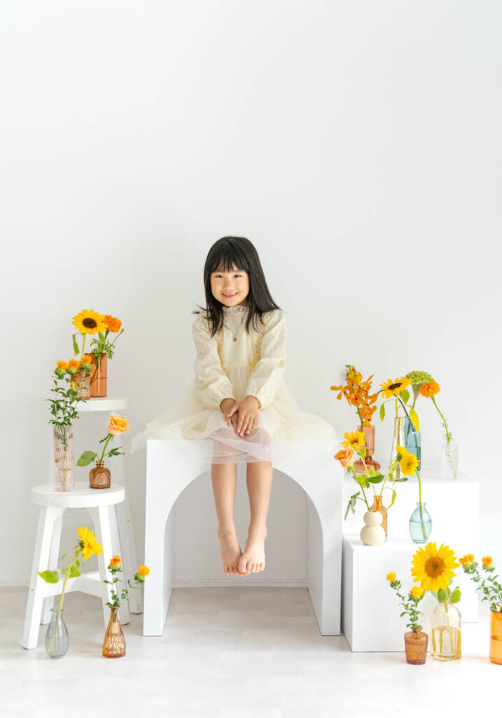 白い空間で花と微笑む少女のポートレート
