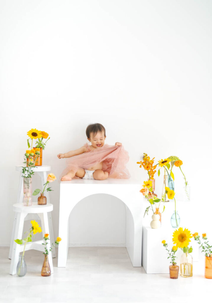 ピンクのドレスの女の子とカラフルな花が彩る明るい写真