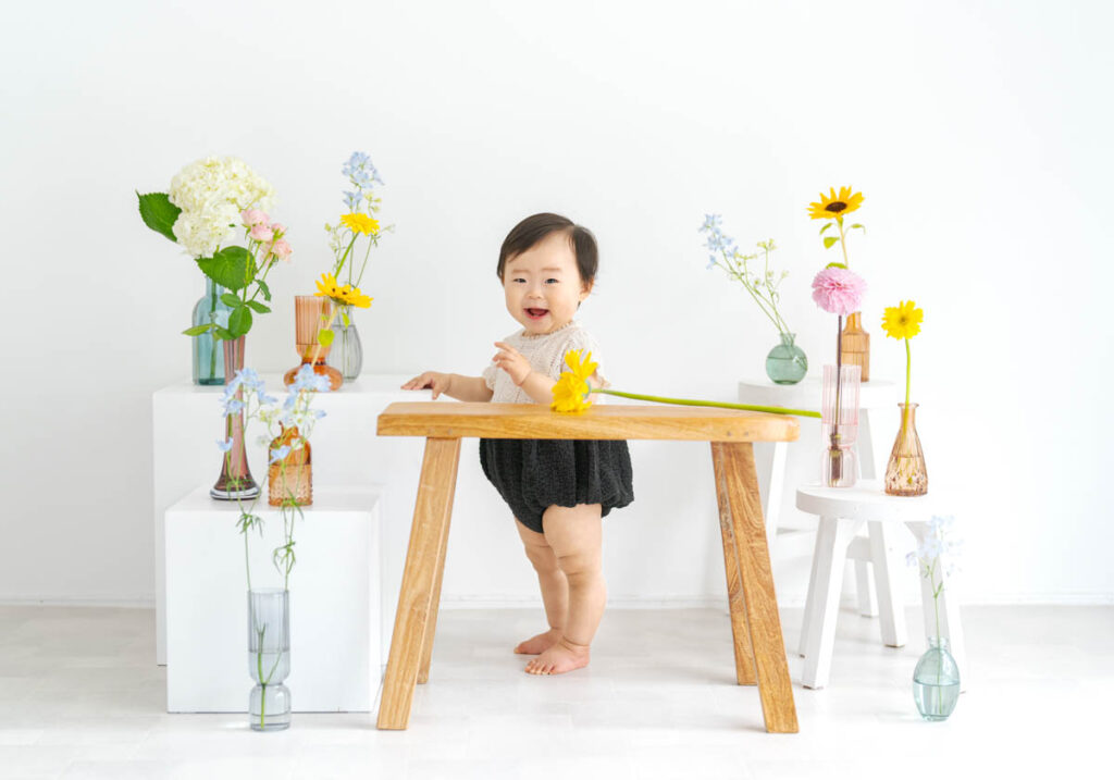 笑顔の赤ちゃんとカラフルな花が彩る明るいナチュラルシーン