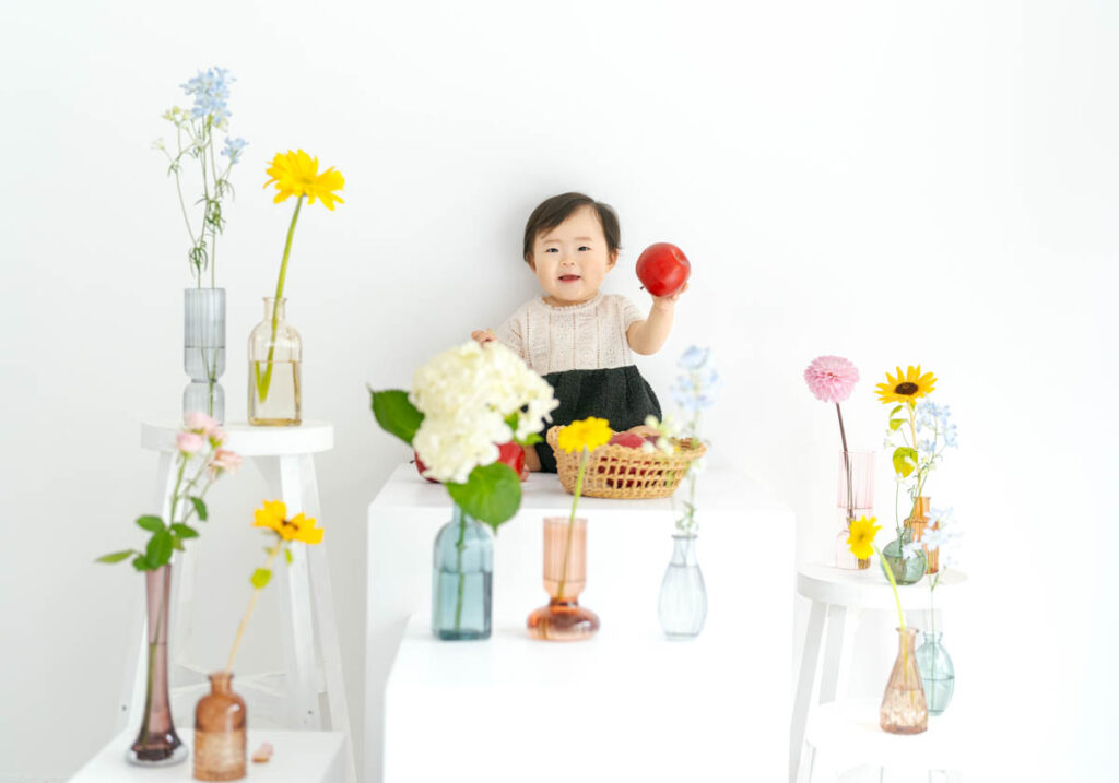 笑顔の子どもと色とりどりの花が咲く白い空間