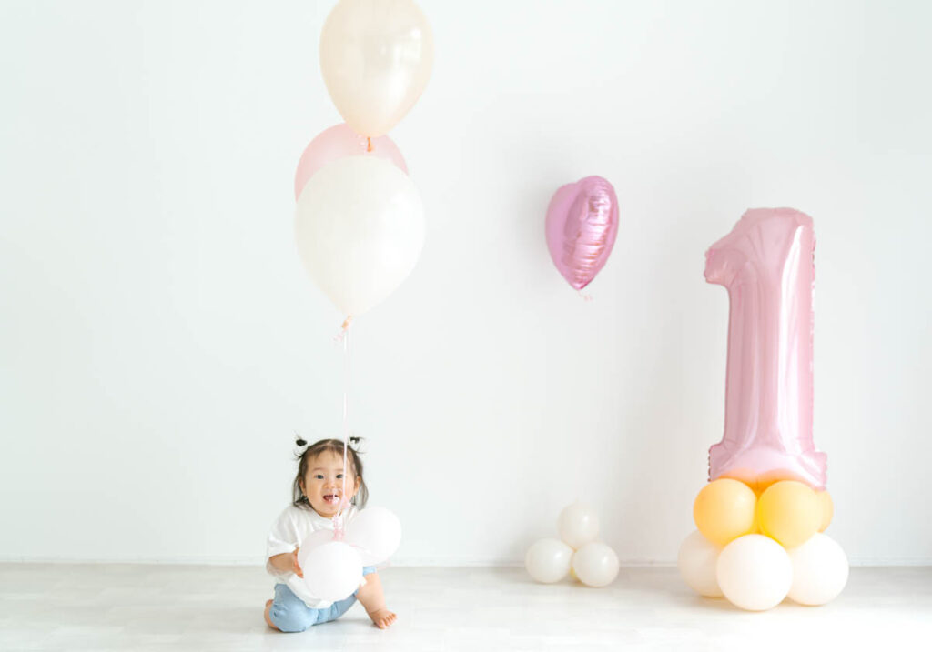 1歳誕生日の赤ちゃんとカラフルなバルーンが微笑む可愛い記念写真