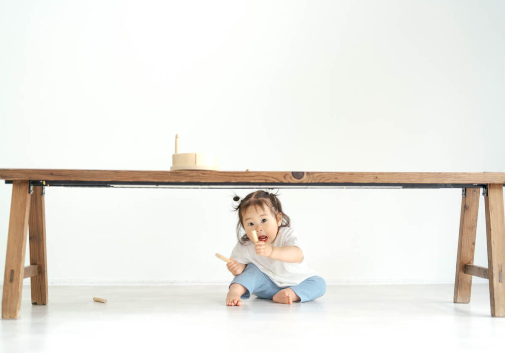 木のテーブルの下で遊ぶ幼い女の子の可愛いひととき