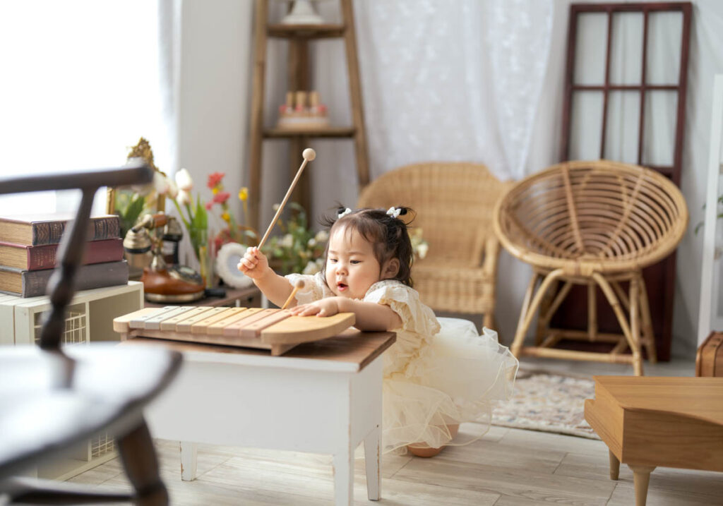 木琴を奏でる幼い女の子と柔らかな光のリビング風景