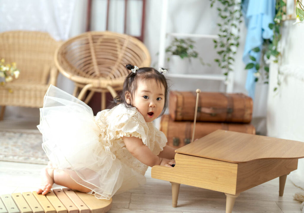 幼い女の子が木製ピアノで遊ぶ可愛いチュチュ姿の瞬間