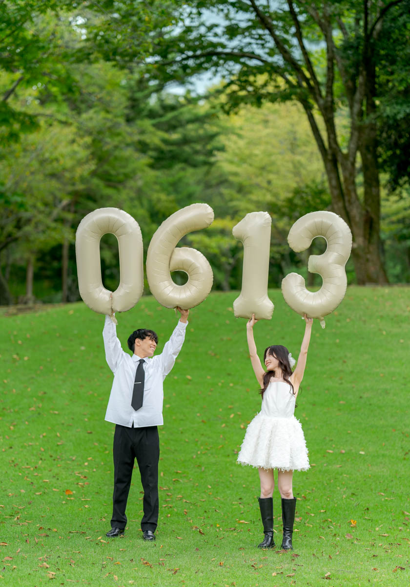 公園で数字バルーンを持ち記念日を祝う笑顔のカップル