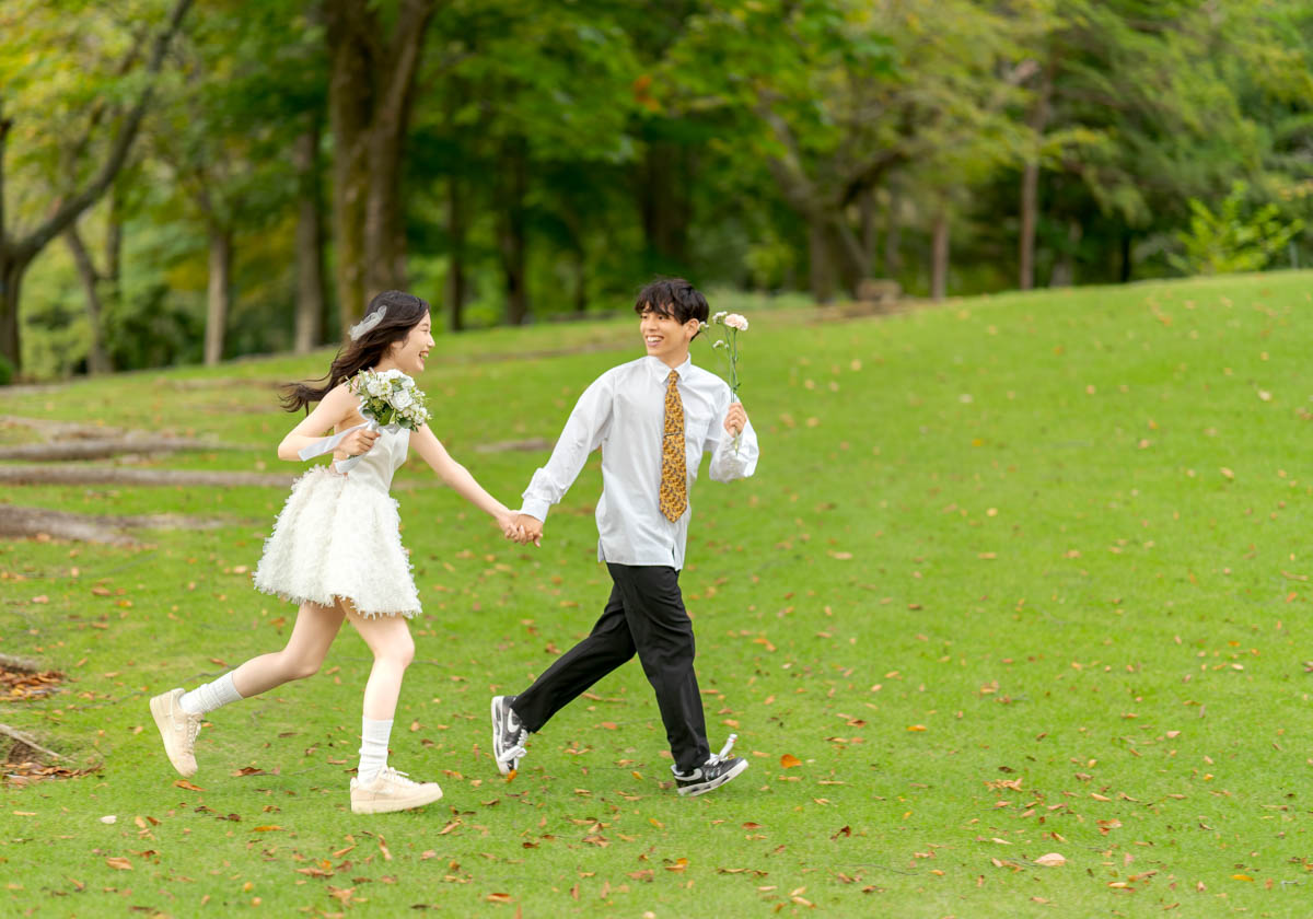 初夏の草原を手を取り合い走る幸せそうな若いカップル