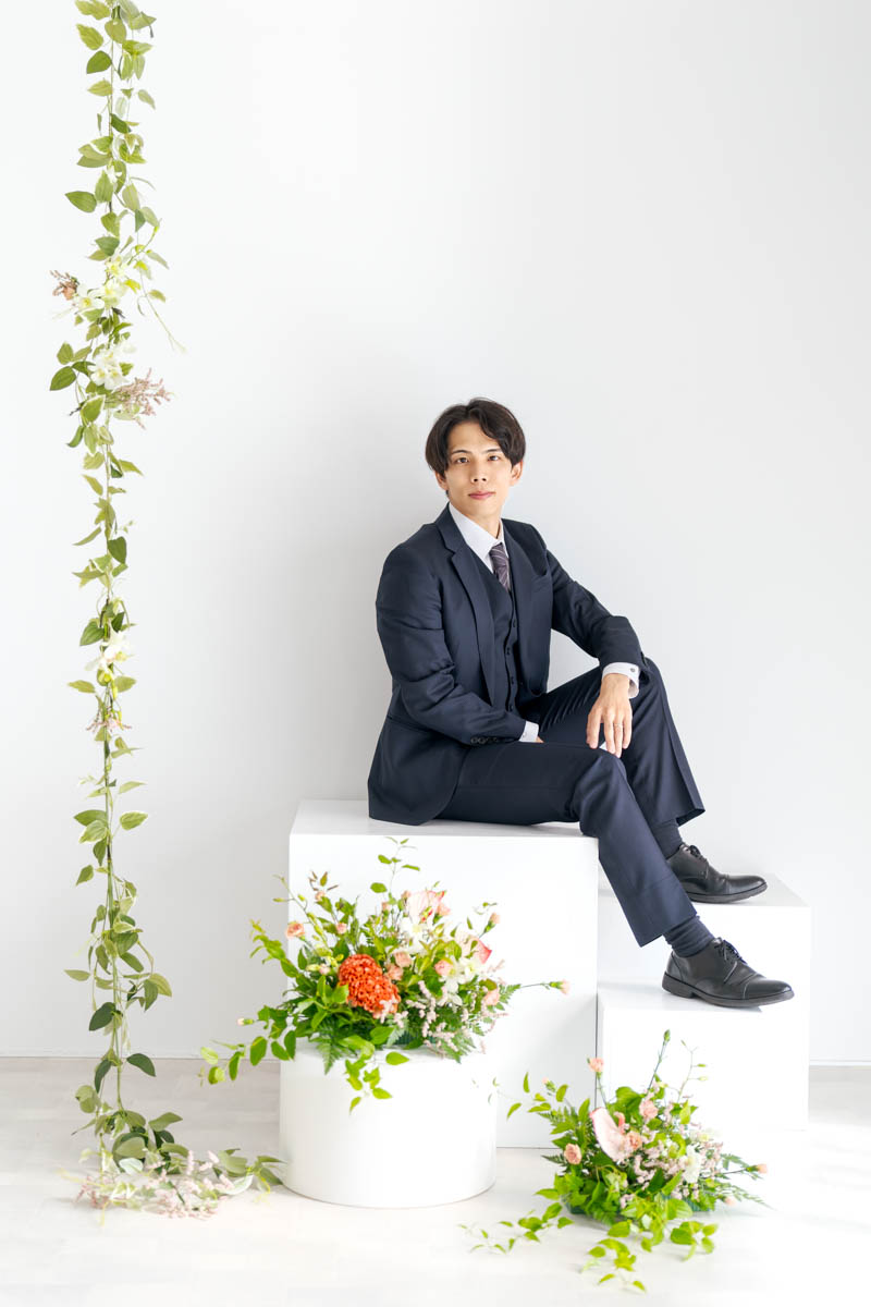 ネイビースーツの男性と華やかな花が映えるエレガントなポートレート