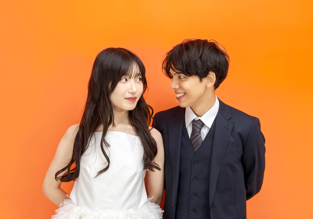 オレンジ背景で見つめ合うカップルの幸せな笑顔