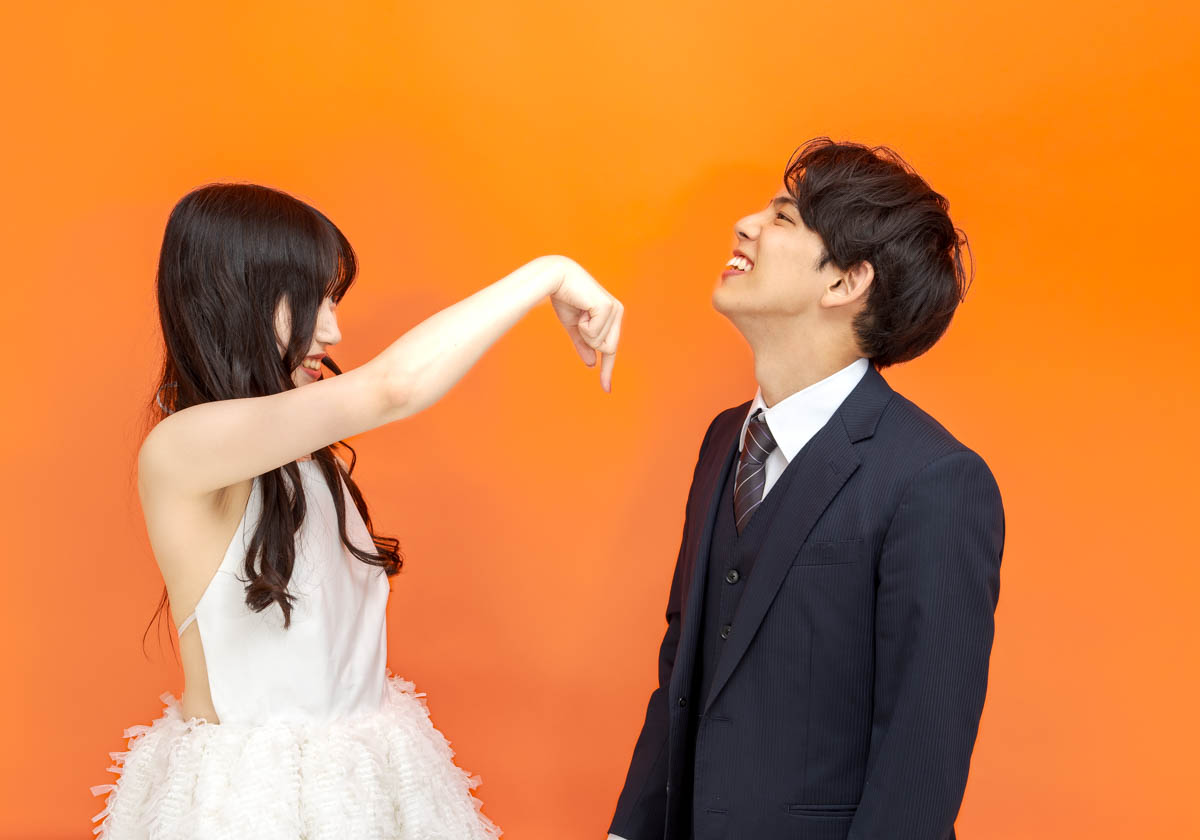 オレンジ背景で微笑み合う男女の楽しいポートレート