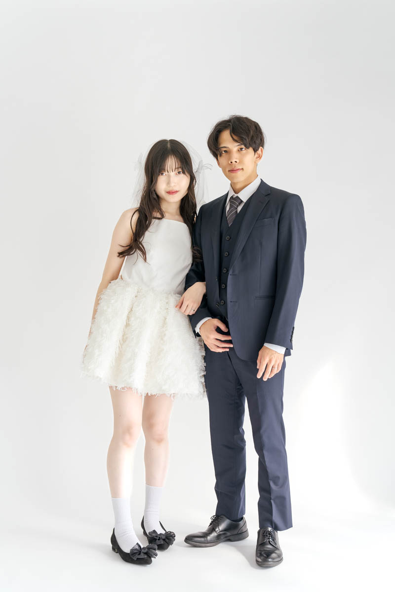 白いドレスとネイビースーツの若いカップルが並ぶおしゃれなポートレート