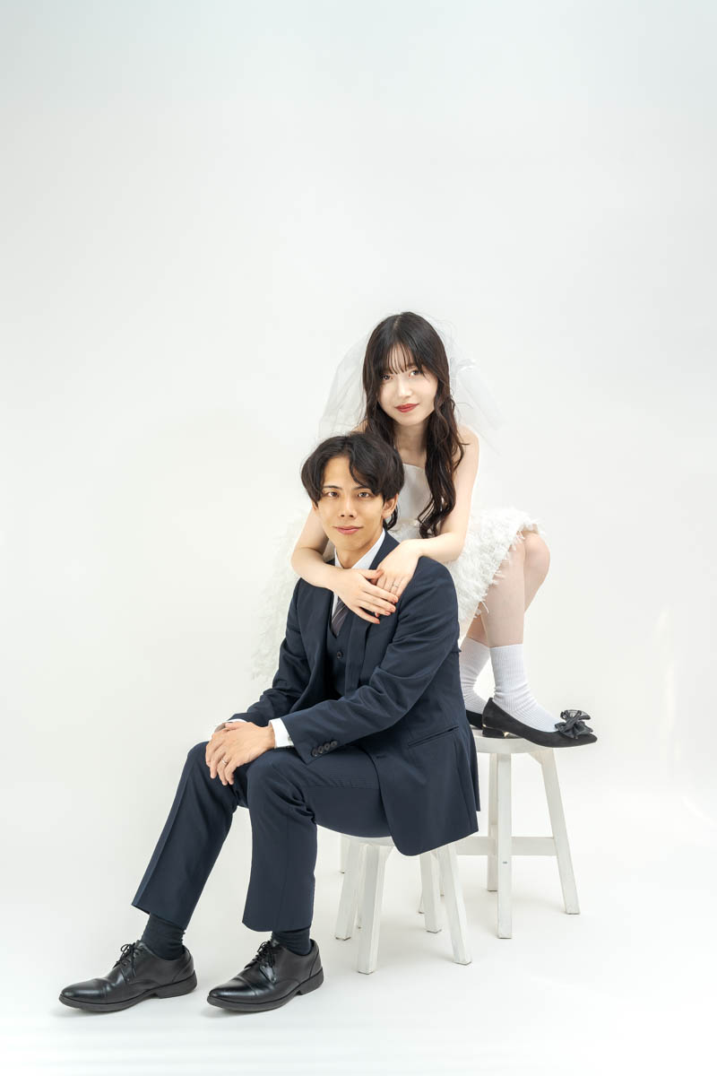 白い背景で寄り添うスーツ姿の男性と白いドレスの女性ポートレート