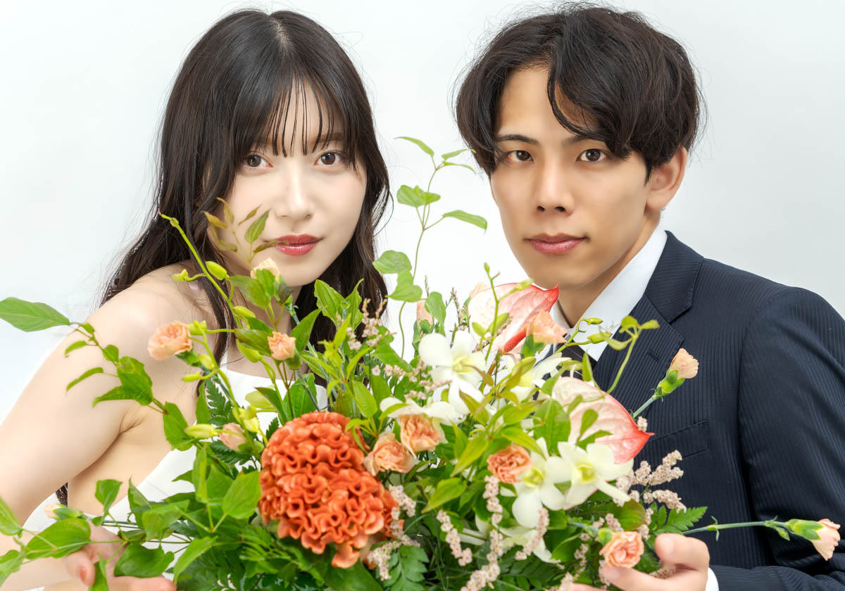 白背景で花束を抱くロマンチックなカップルのポートレート