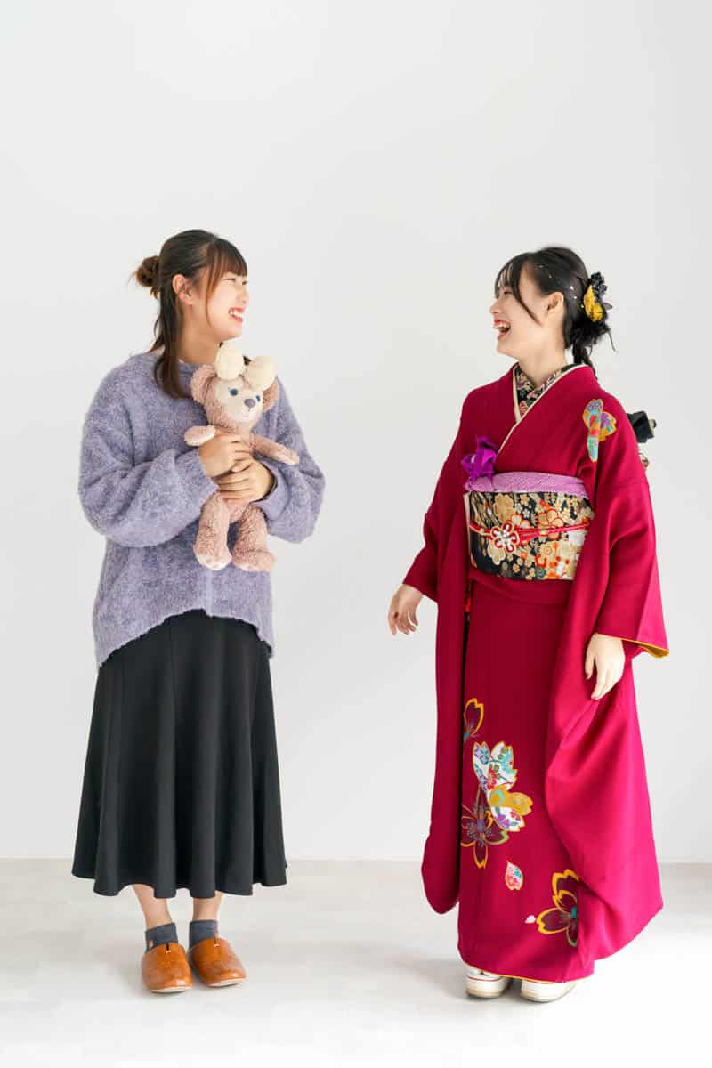 紫のセーターと赤い着物で笑い合う友人たちの温かな瞬間