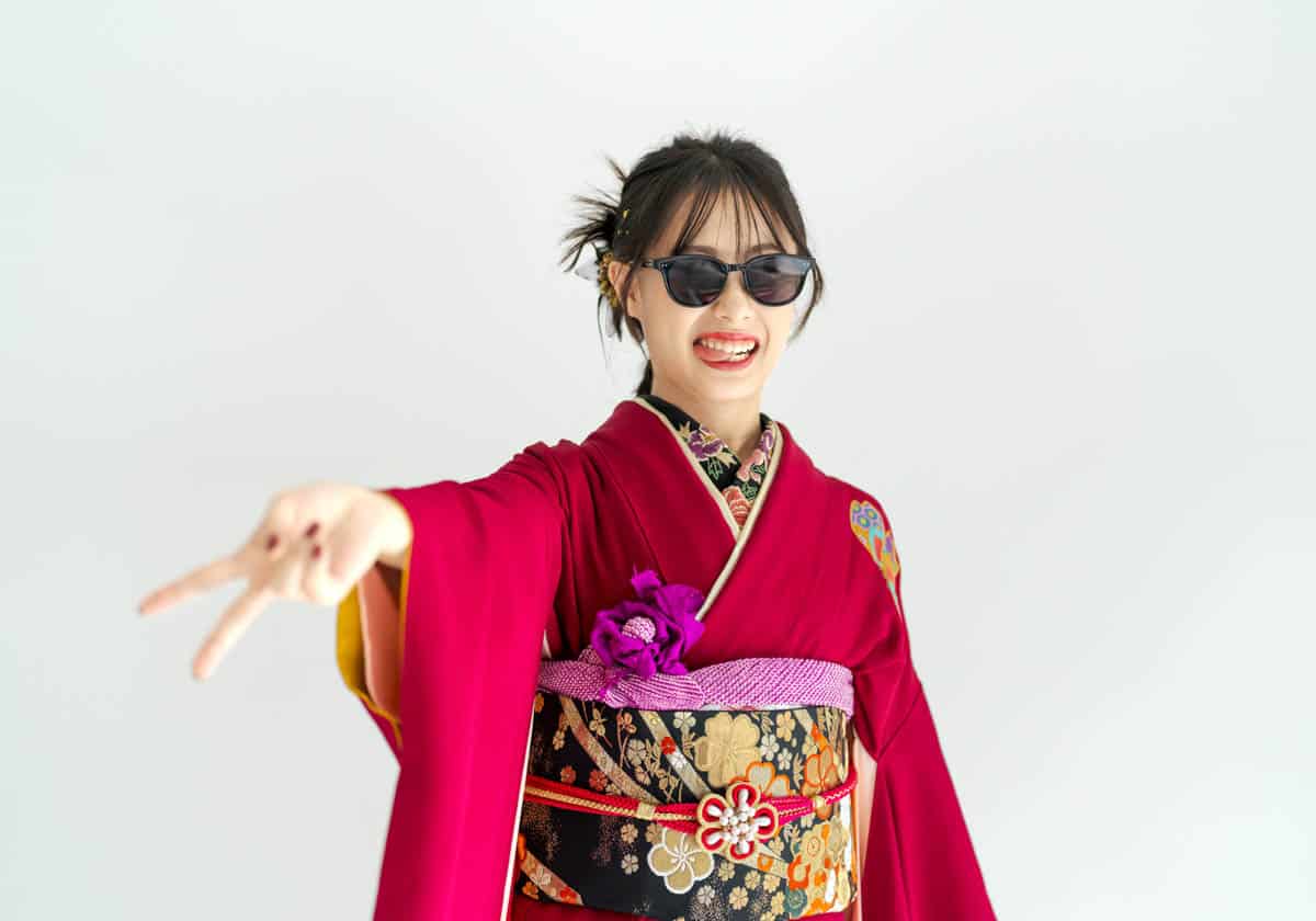 赤い着物とサングラスで笑顔ポーズの現代的な女性