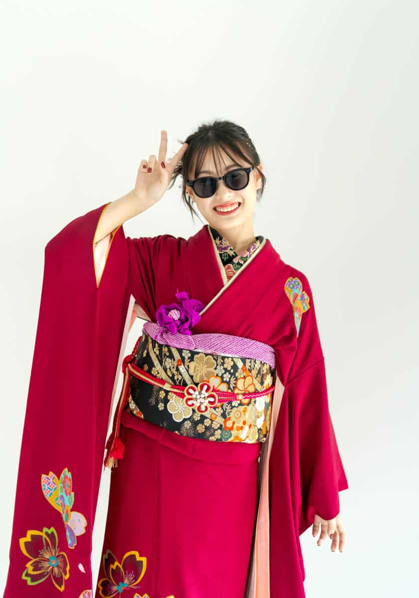 赤い着物と紫の花飾りで笑顔を見せる女性